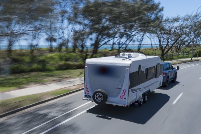 A caravan being towed down a country road.