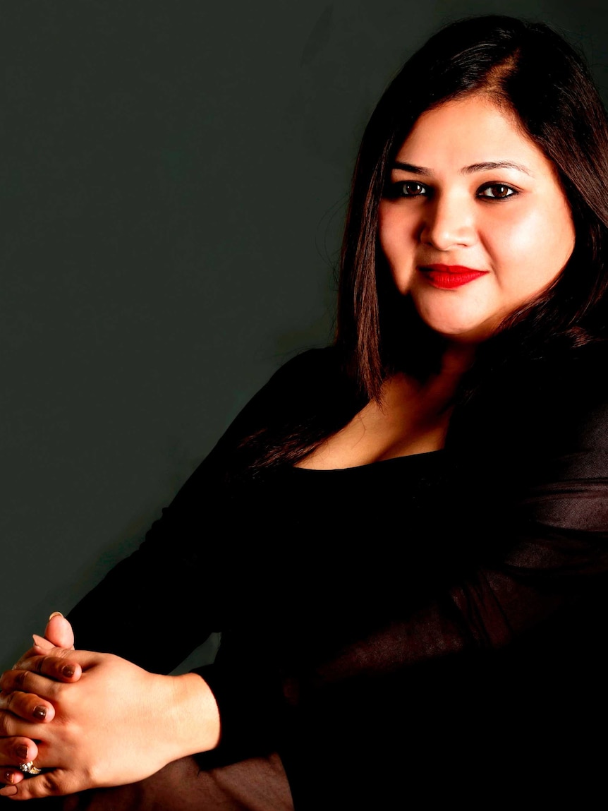 Woman with long brown hair and brown eyes smiles towards the camera.