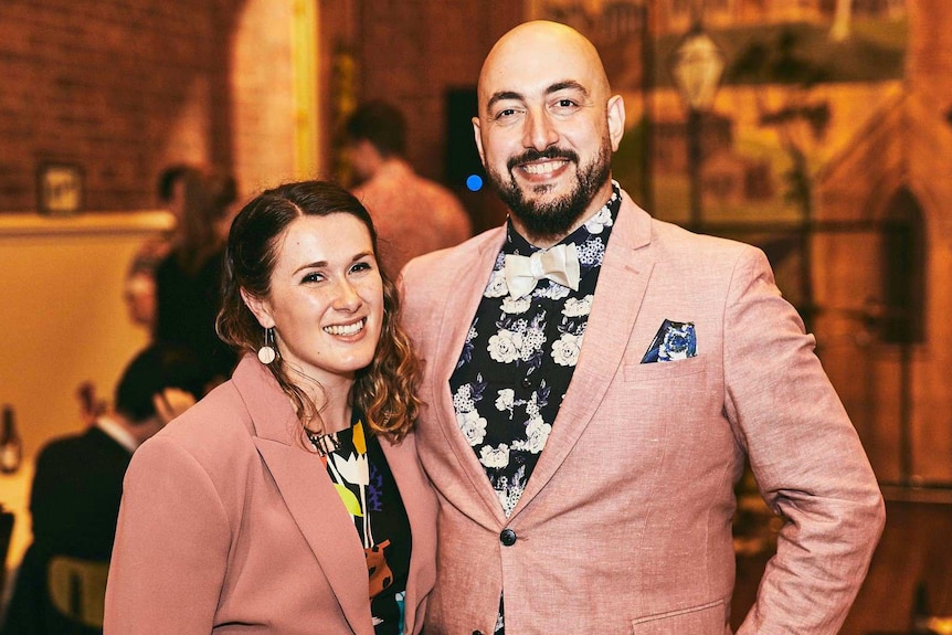 A woman and man both wear pink jackets