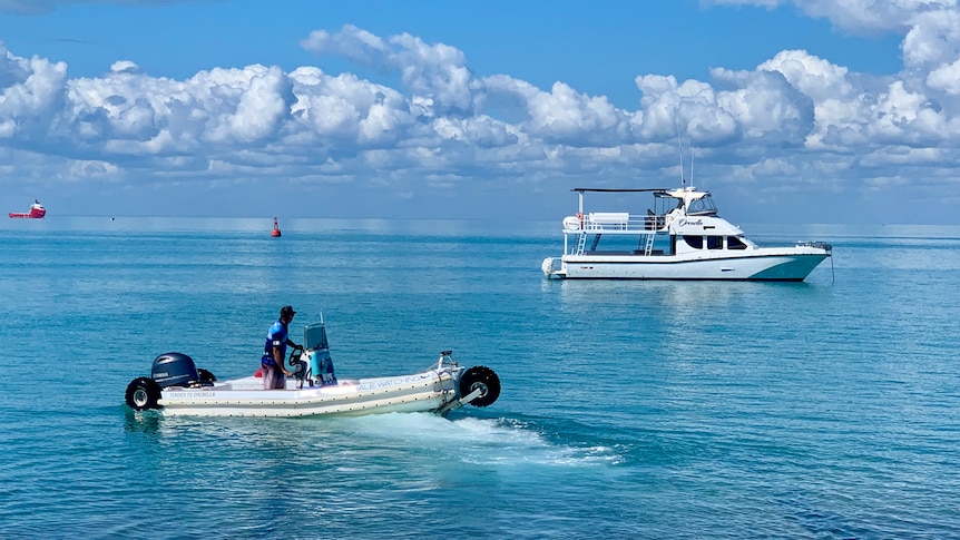 Boats on a blue sea with clouds in the distance.