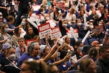 A tight shot of a crowd of nurses holding up signs calling for nurse-to-patient ratios