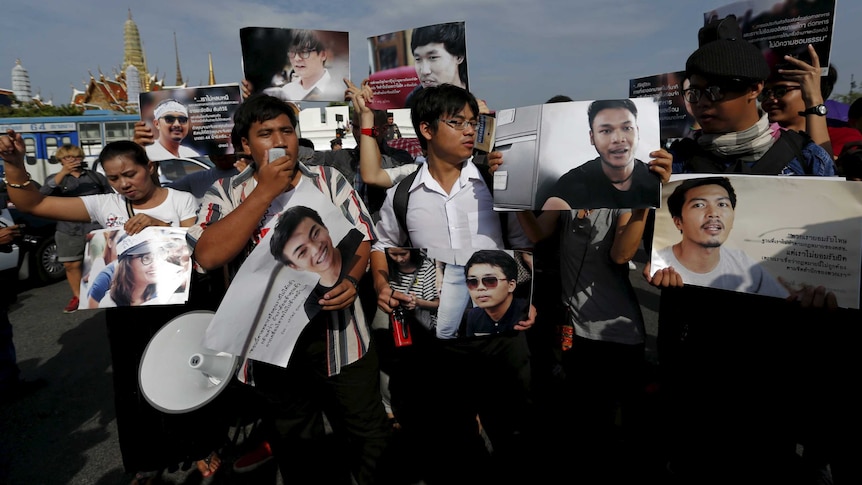 Activists hold up pictures of the 14 students who had been held for holding anti-coup protests, during a rally outside the military court in Bangkok, Thailand, July 7, 2015