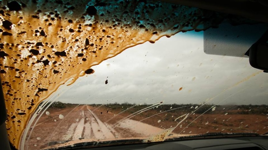 View from the dash of a car of a wet and muddy road in far west New South Wales.