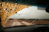 View from the dash of a car of a wet and muddy road in far west New South Wales.