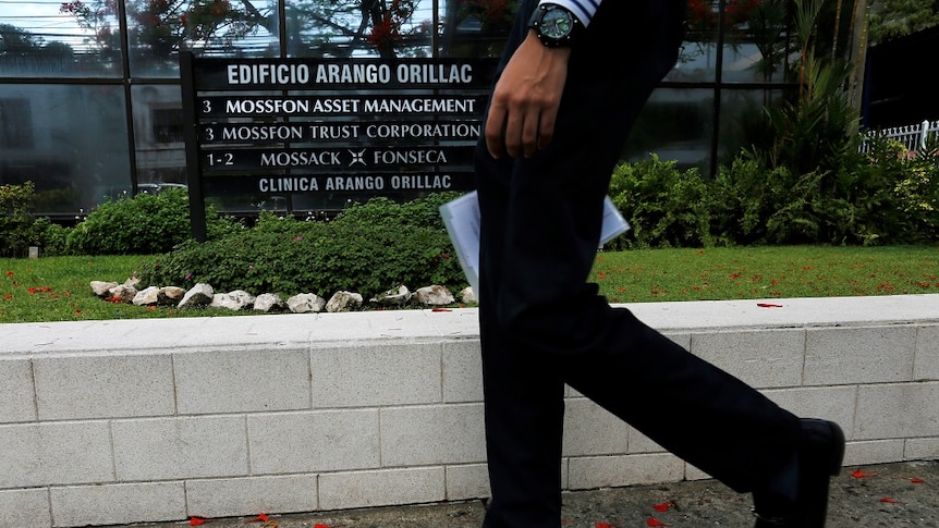 A man walks past a building sign showing Mossack Fonseca.