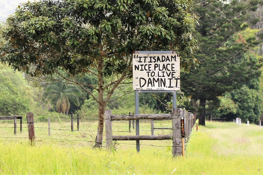 A sign on a rural property saying "It is a dam nice place to live.  Damn it."