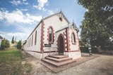 A beautiful old chapel with arched windows and careful brickwork stands on a leafy block