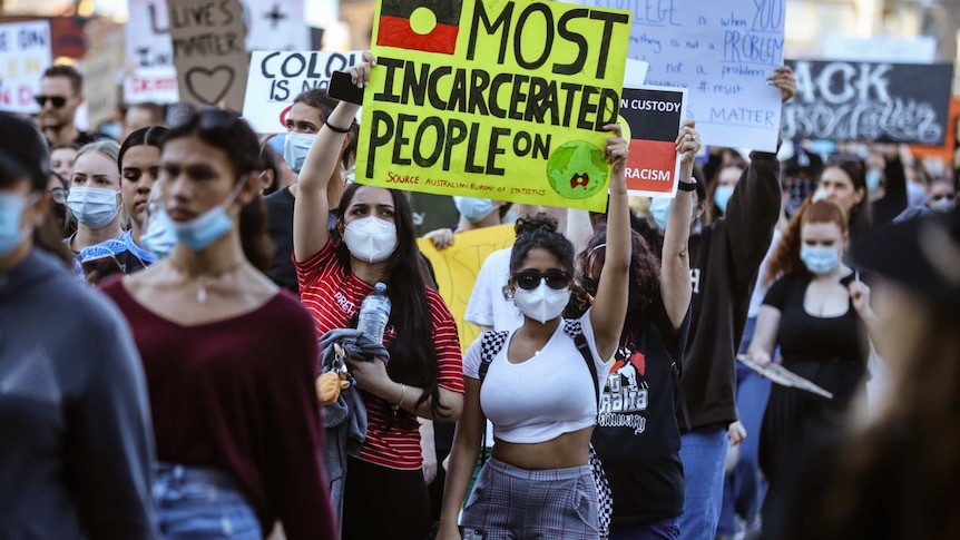 A group of people hold signs at the Black Lives Matter protest in Brisbane