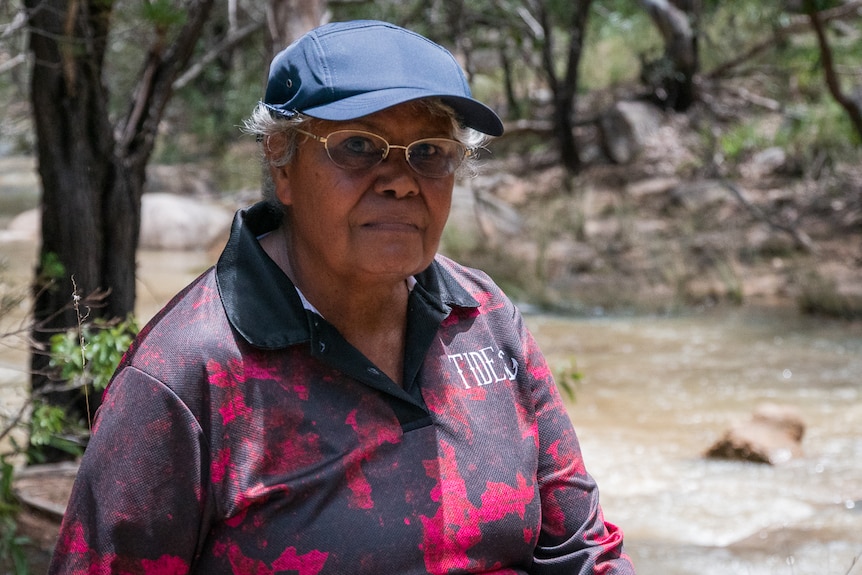 Older Aboriginal woman sits by river