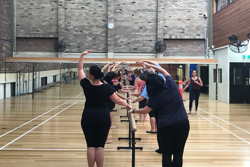 Older women standing at a bar learning ballet