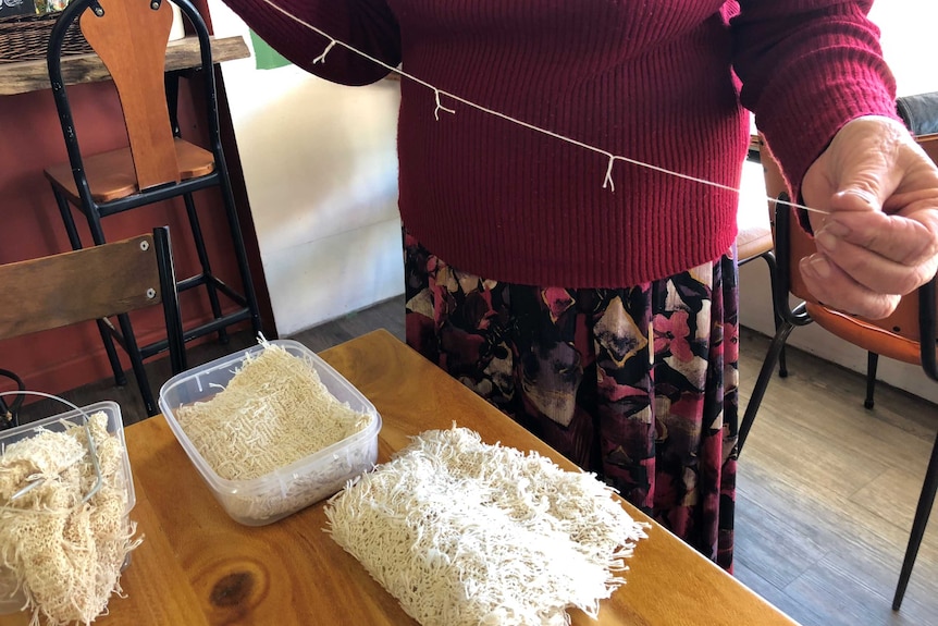 a lady holding a string of tea bag strings