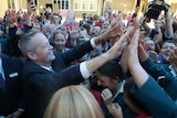 Bill Shorten offers double high fives as he's surrounded by a crowd of school students
