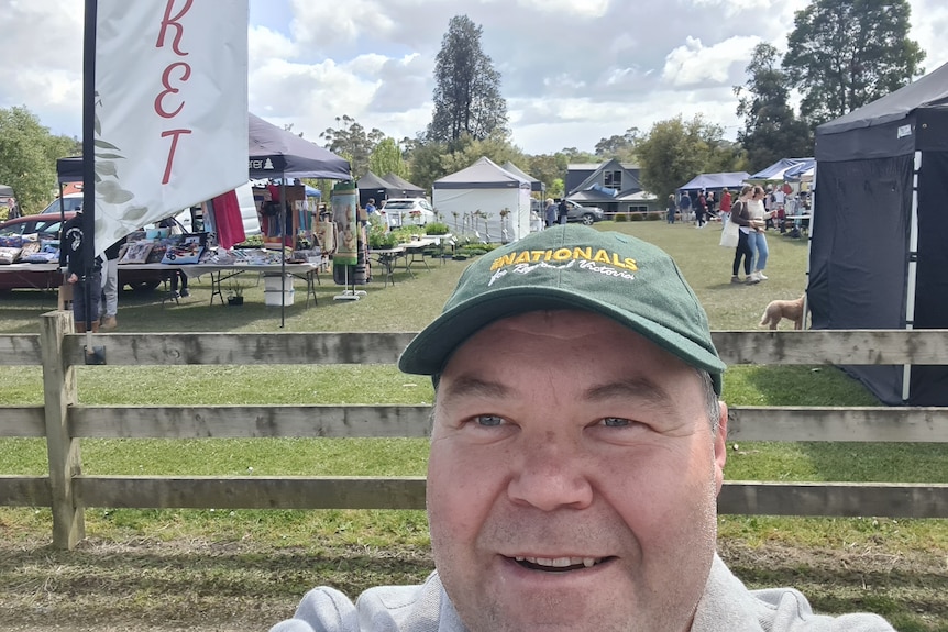 A selfie of a middle-aged man wearing a National party hat at a country market 