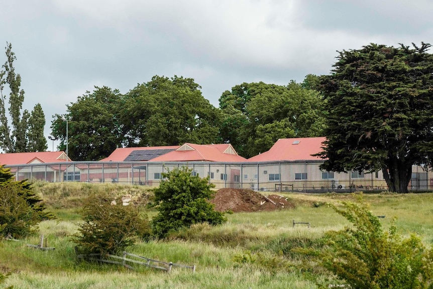 A collection of small buildings with red roofs behind a wire fence