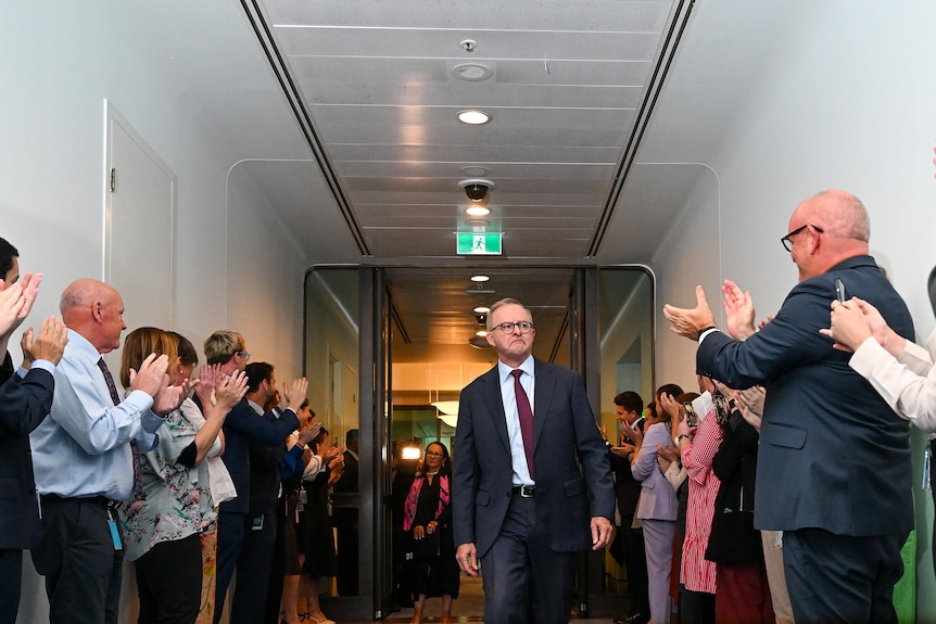 People line the corridors to applaud Anthony Albanese as he walks down the middle of a corridor