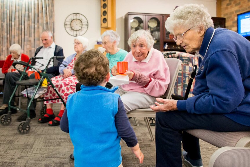 A toddler entertains residents in an aged care home