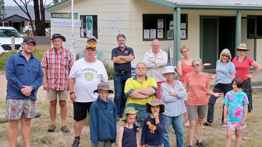 Group of residents looking anger standing outside a small hall.