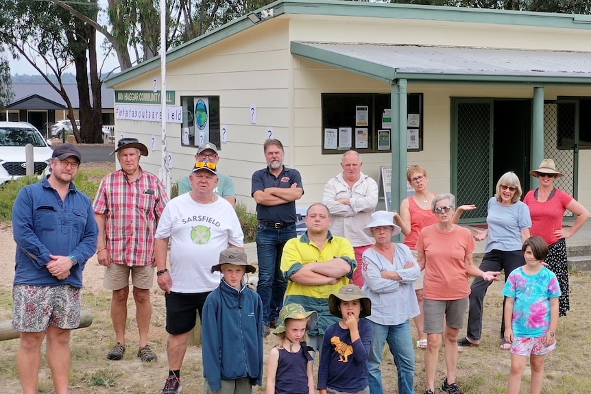 Group of residents looking anger standing outside a small hall.