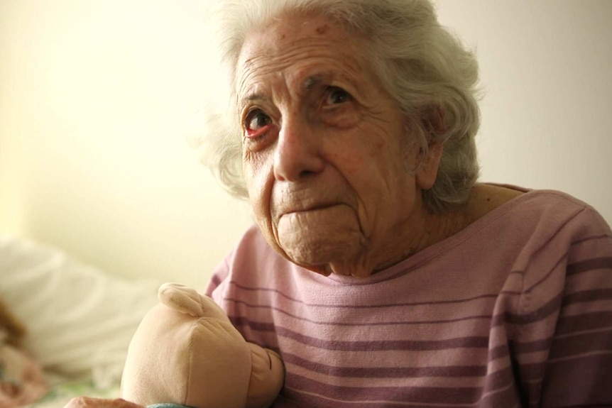 Portrait of an elderly lady clutching her teddy.