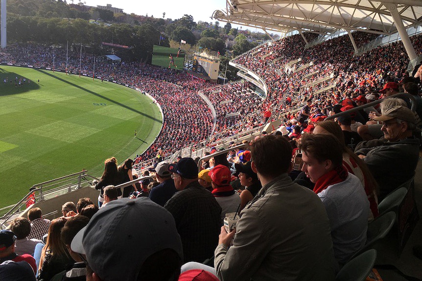 Large crowds of people sitting in a stadium, mostly wearing red.