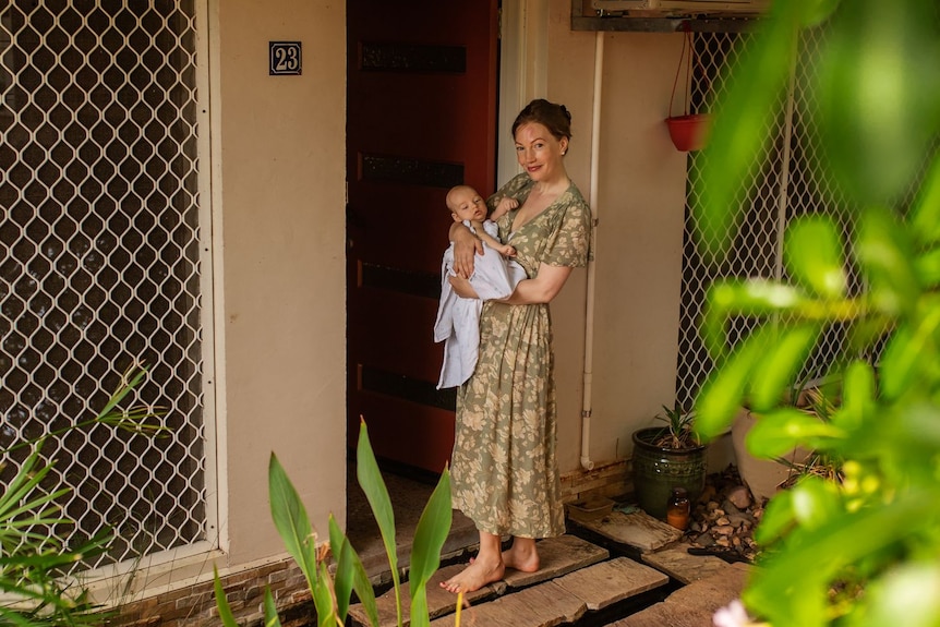 Photo of a woman carrying a newborn in a lush garden