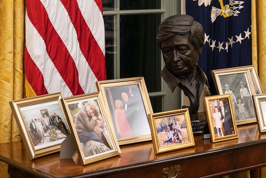 Photographs of Joe Biden and his family sit on a table in the Oval Office alongside a bust of Cesar Chavez.