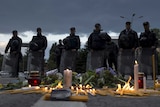 Macedonian police stand in front of a memorial for the victims of a gun battle in Kumanovo
