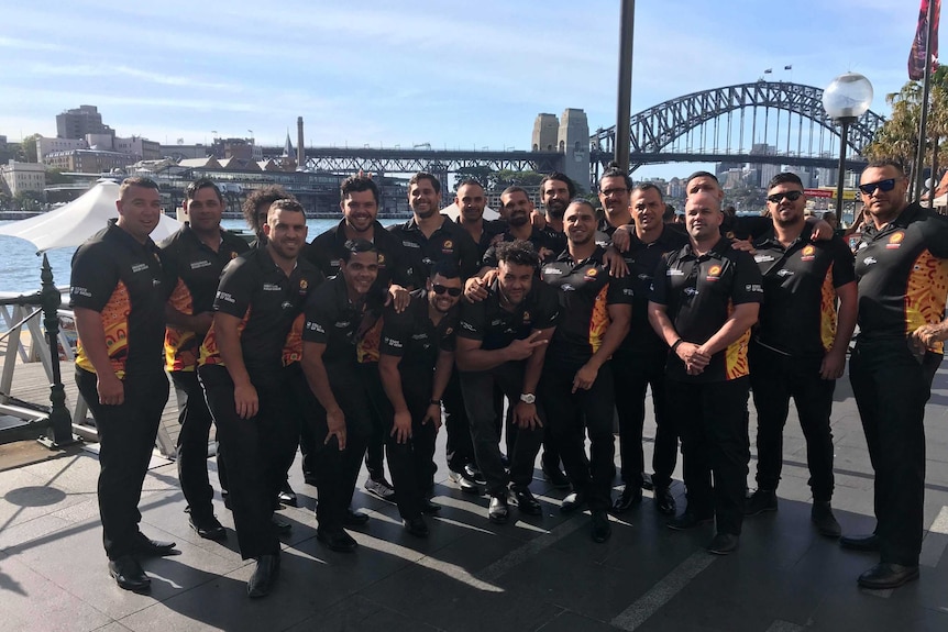 A group of men stand in front of the Harbour Bridge.