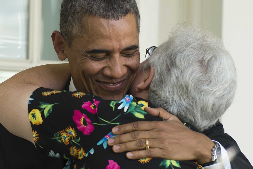 US President Barack Obama smiles as he hugs an older woman in a floral shirt.