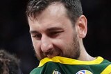 Andrew Bogut puts his dark green singlet in his mouth as teammates crowd around him