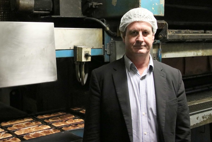 Midas bakery owner Conrad Mias standing in front of bakery machinery