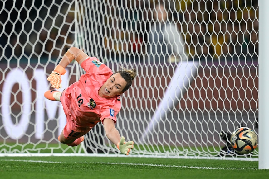 A goalkeeper dives trying to stop a ball from going into the net.