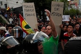Protesters in the streets of Bolivia holidng up sign with Fraude written on them.