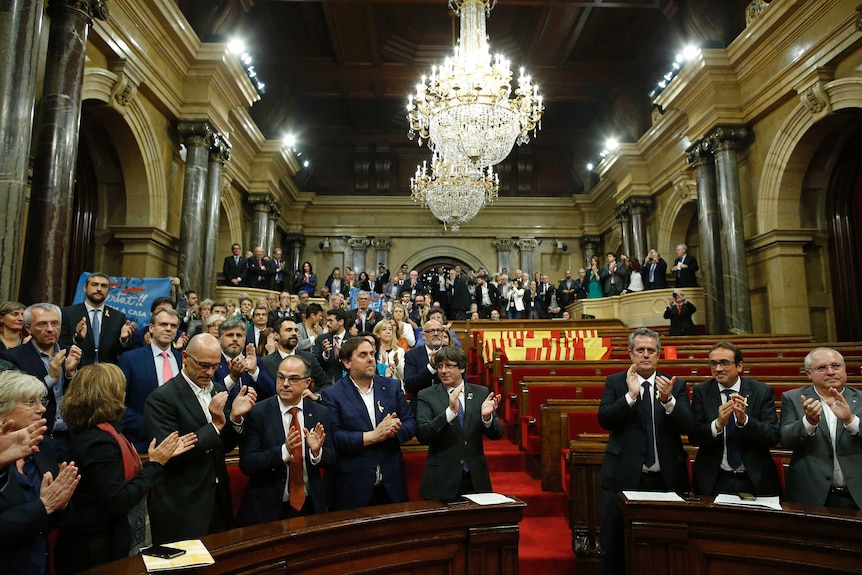 Catalan President Carles Puigdemont and others applaud after a vote on independence in the parliament.