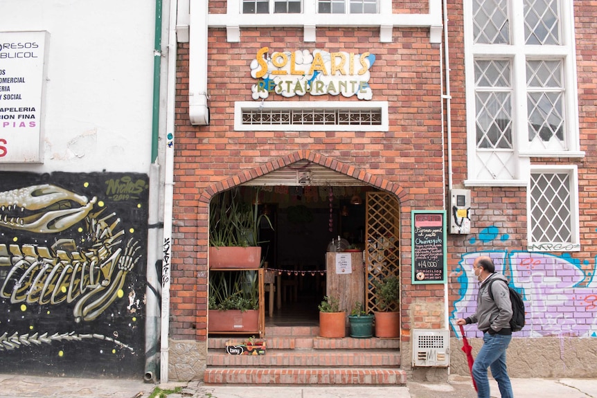 A man walks in front of a red brick building with colouful murals painted on it