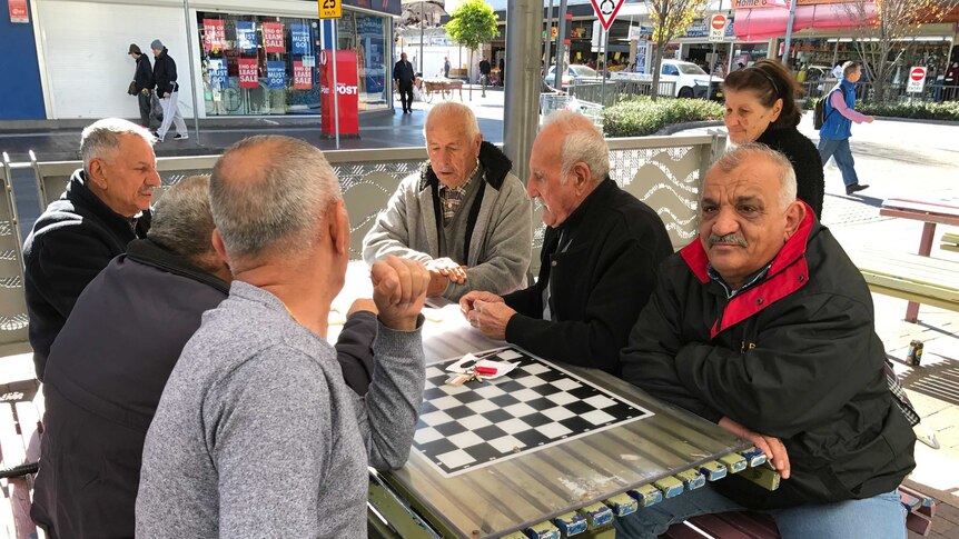 Residents of Fairfield in Sydney's west sit at a public table and talk