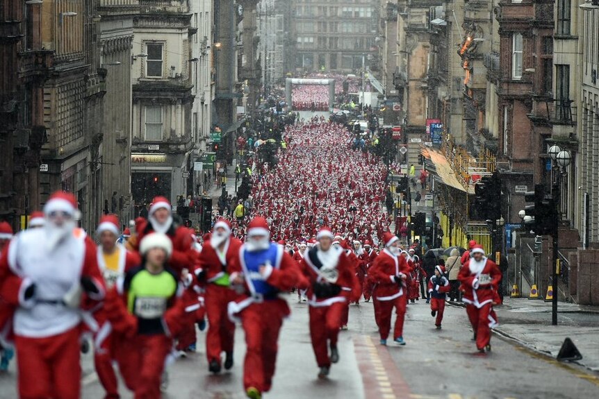 Hundreds of people dressed as Santas run down a street in Glasgow.