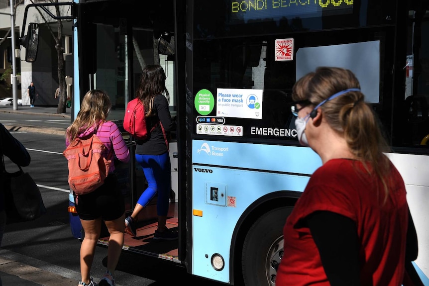 people boarding a bus, one woman wearing a mask