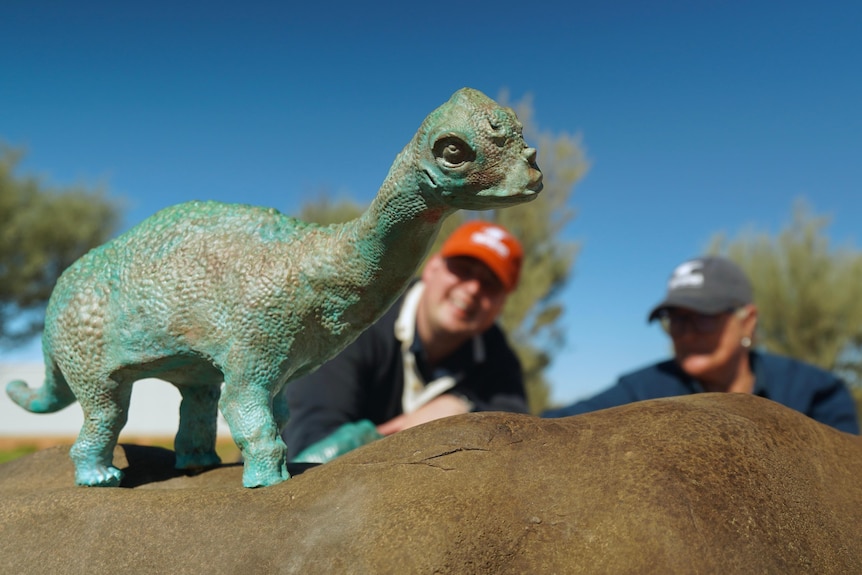 Dinosaur sculpture with two people sitting in background