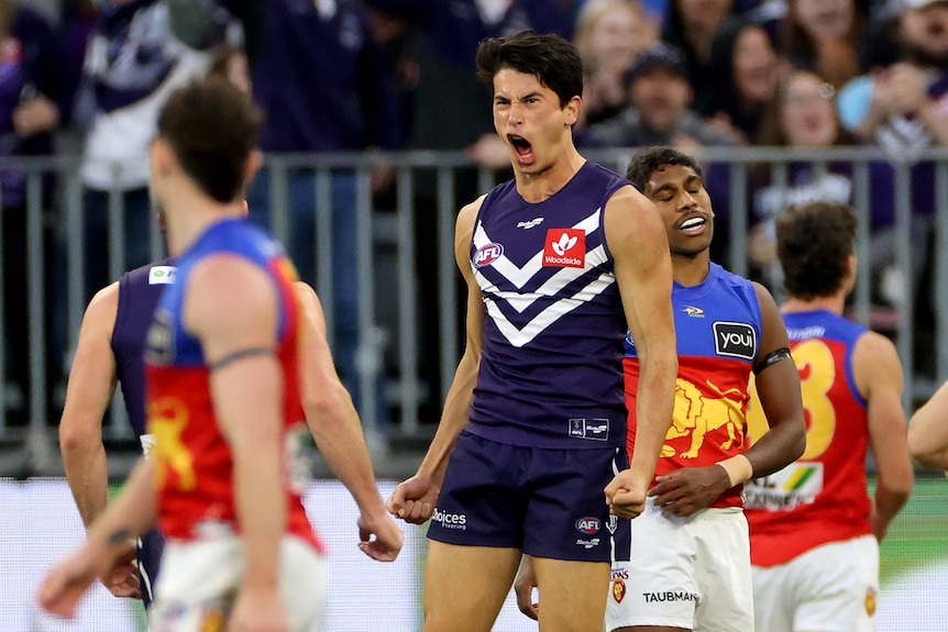 Bailey Banfield screams in delight as disappointed Lions players surround him