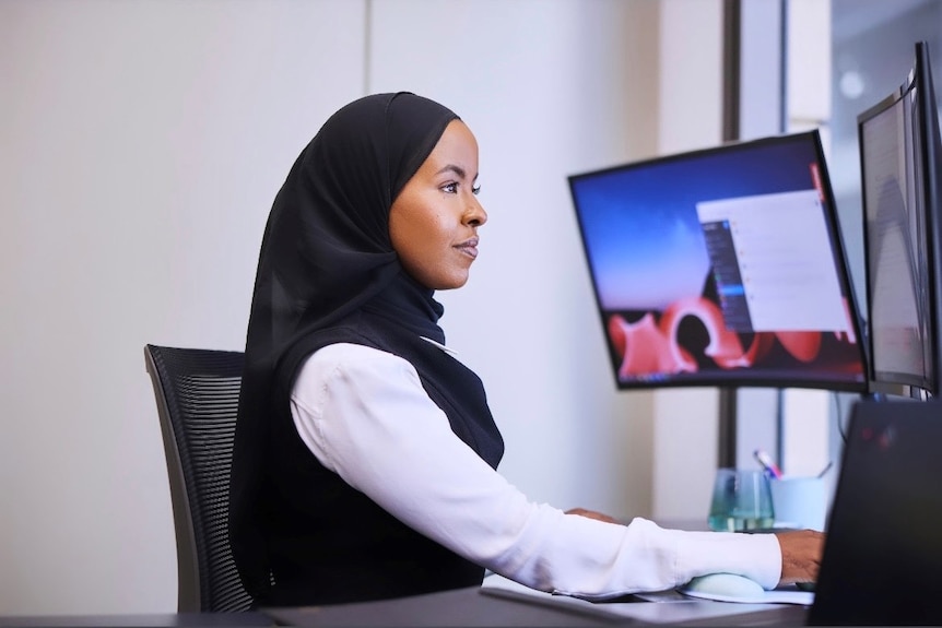 A woman in a headscarf sitting at her computer  