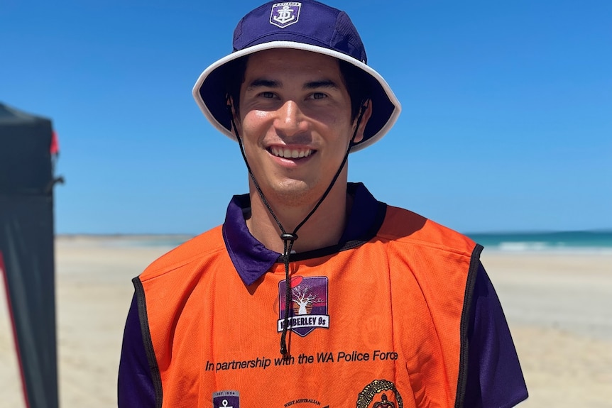 man smiles at camera, wearing a bucket hat 