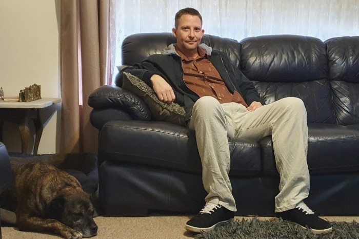 Wodonga veteran Eli Turner sitting on his couch with his dog Jake at his feet.