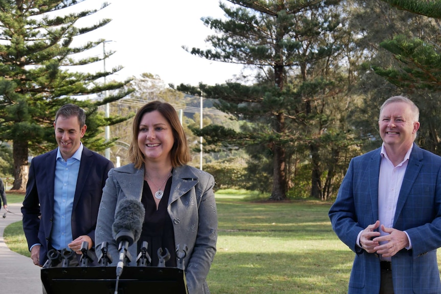 Kristy McBain stands in front of a microphone next to Anthony Albanese and Jim Chalmers