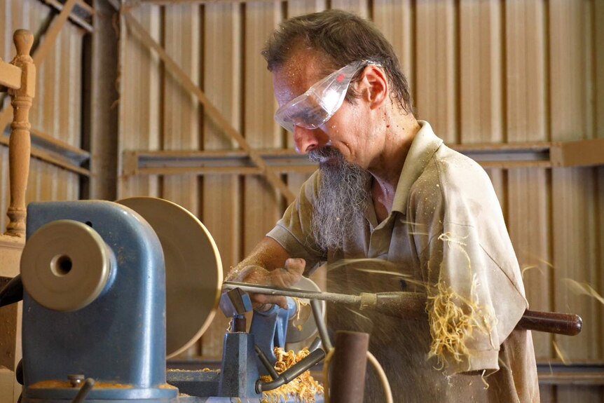 Dale Cordwell holds a wood turning implement while using a lathe