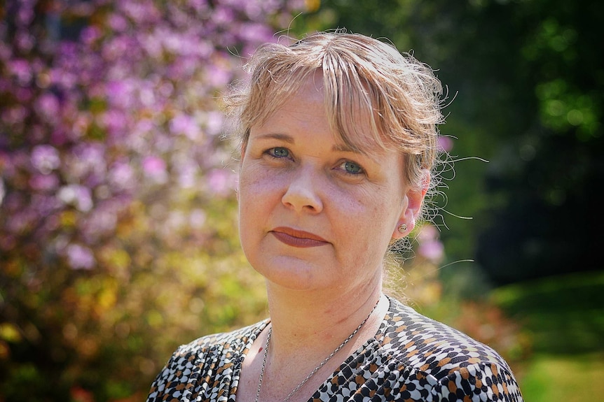 Woman stands in front of purple and green garden backdrop