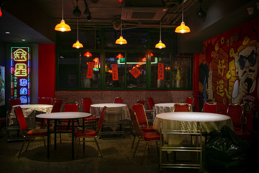餐馆中在铺着白色桌布的桌子旁摆放着红色的空椅子。