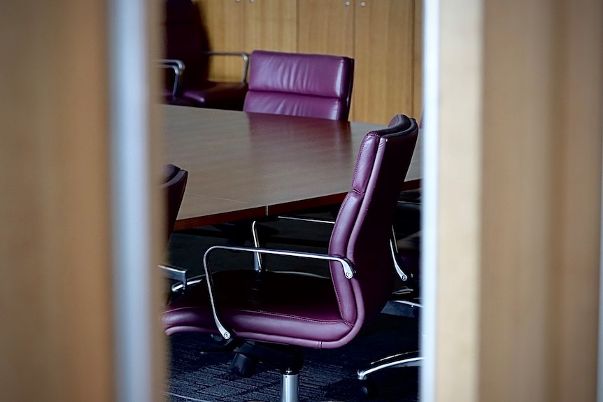 Purple chairs in a boardroom seen through an open door.