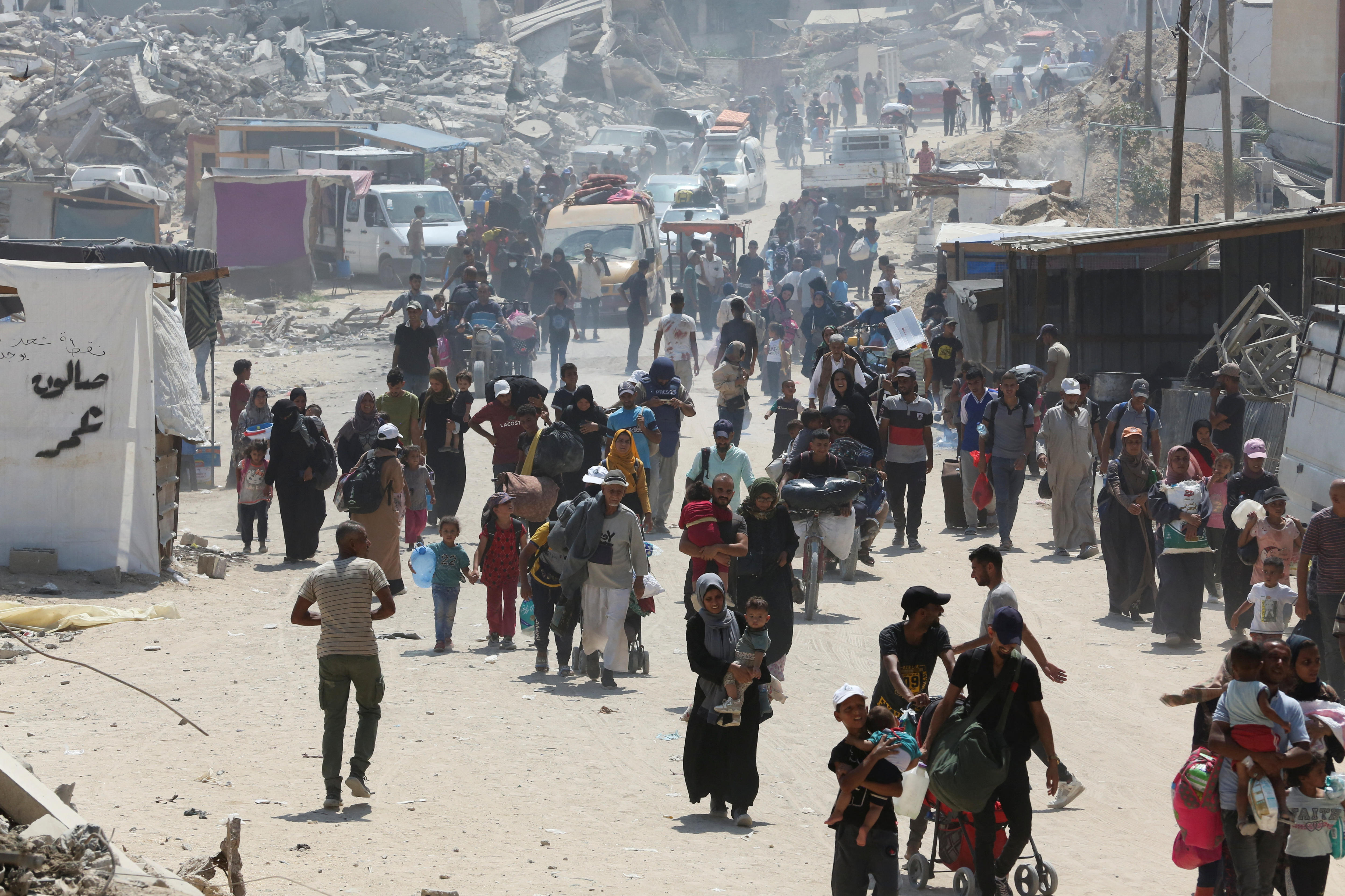 A crowd walking away from an area with damaged tents 