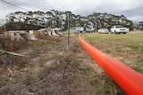 A large orange hose runs along a fenceline in rural Victoria.